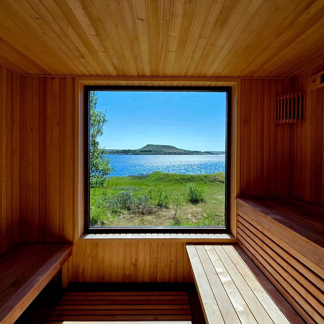 Inside a wood-lined Icelandic sauna, window open to the water